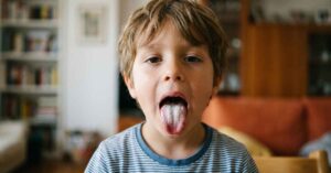 Bambino che tira fuori la lingua bianca