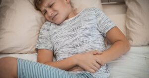 Bambino con mal di pancia sdraiato a letto